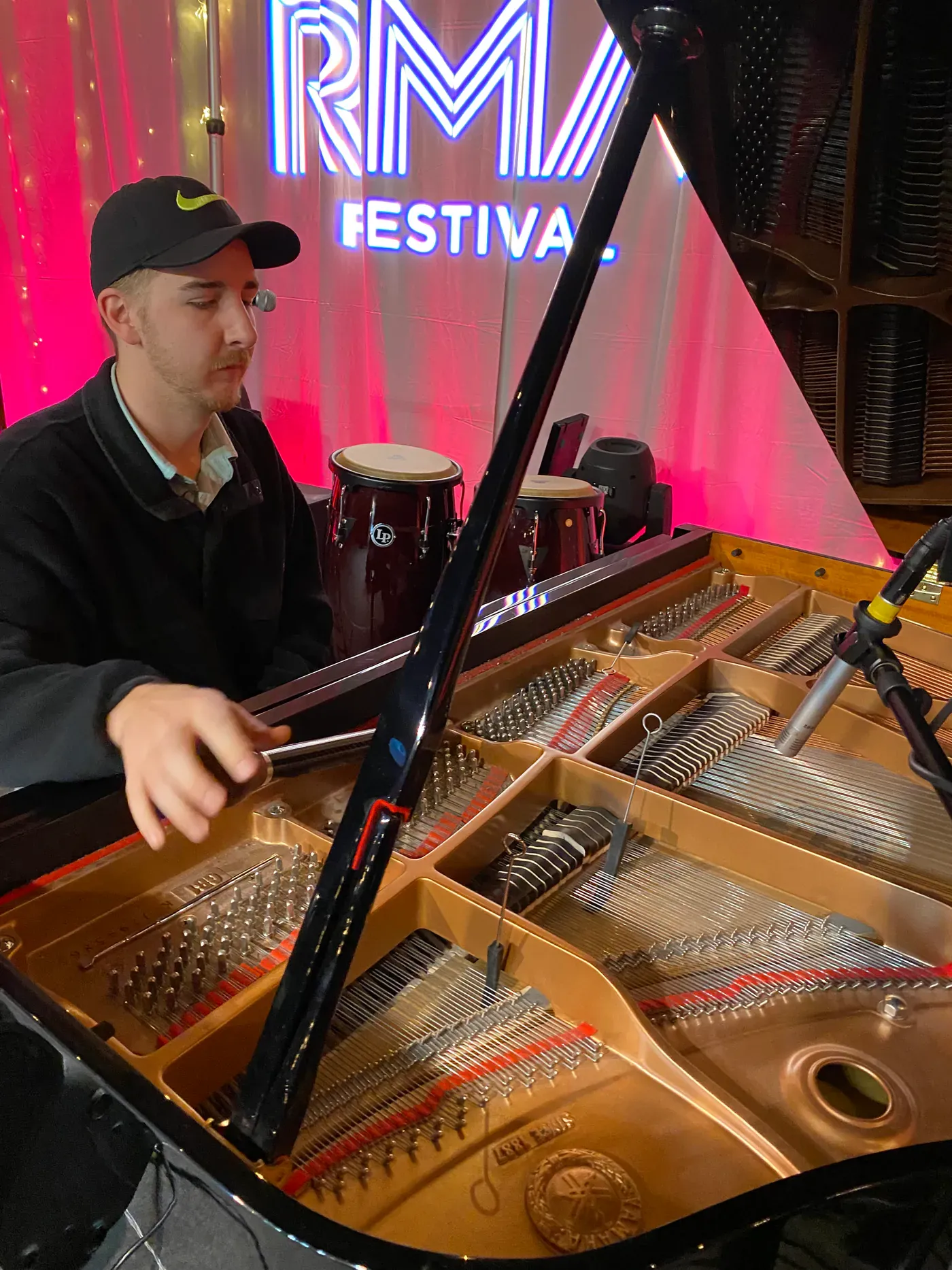 Pierce O’Brien tuning an open grand piano at a festival event