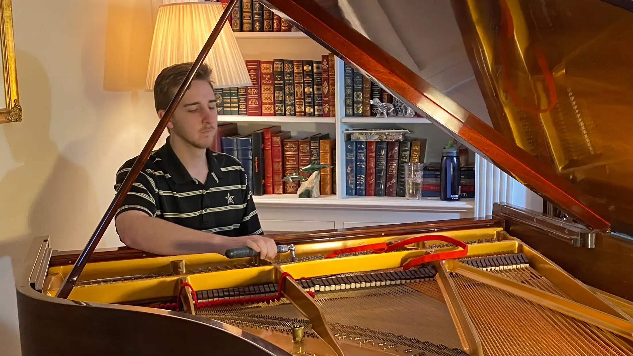 Pierce O’Brien working at the strings of a grand piano
